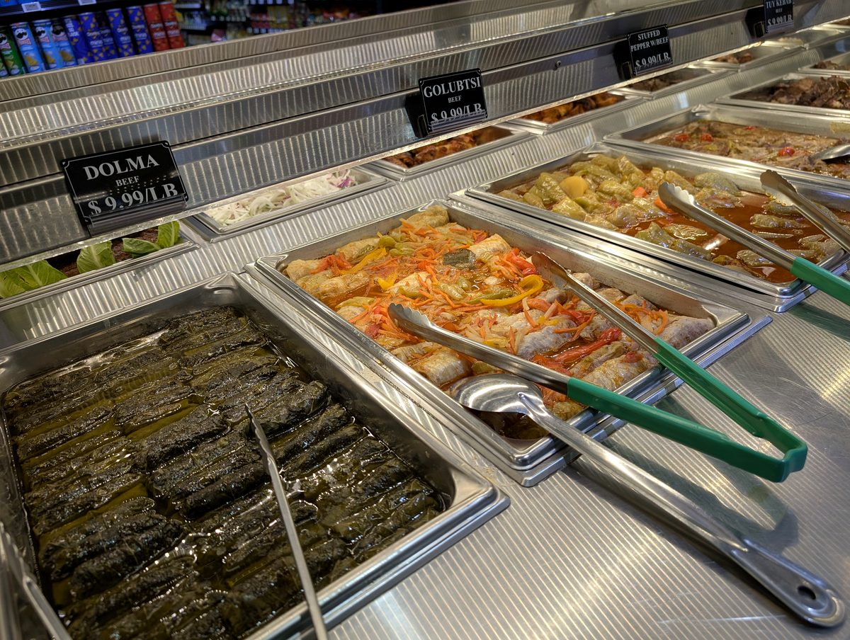 Steam trays of hot prepared food with tongs at the ASR Food Market hot bar.