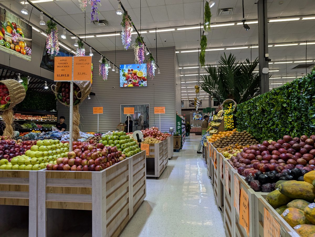 Wooden produce bins of apples and fruit with price signs at ASR Food Market.