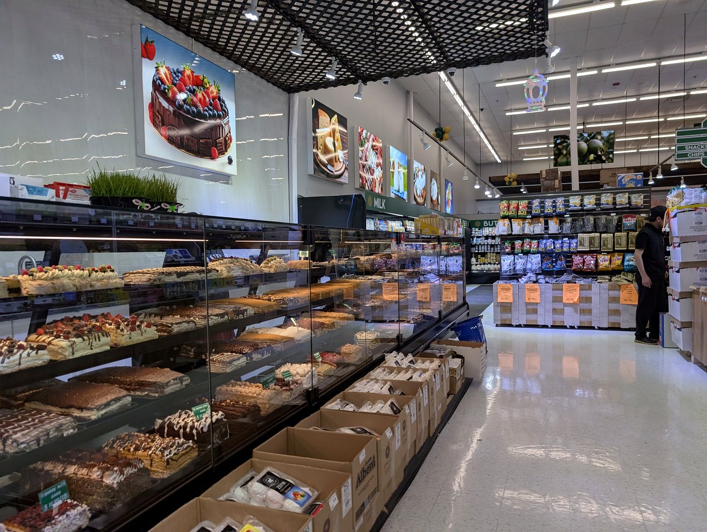 Curved glass bakery cases of cakes, pastries and breads at ASR Food Market.