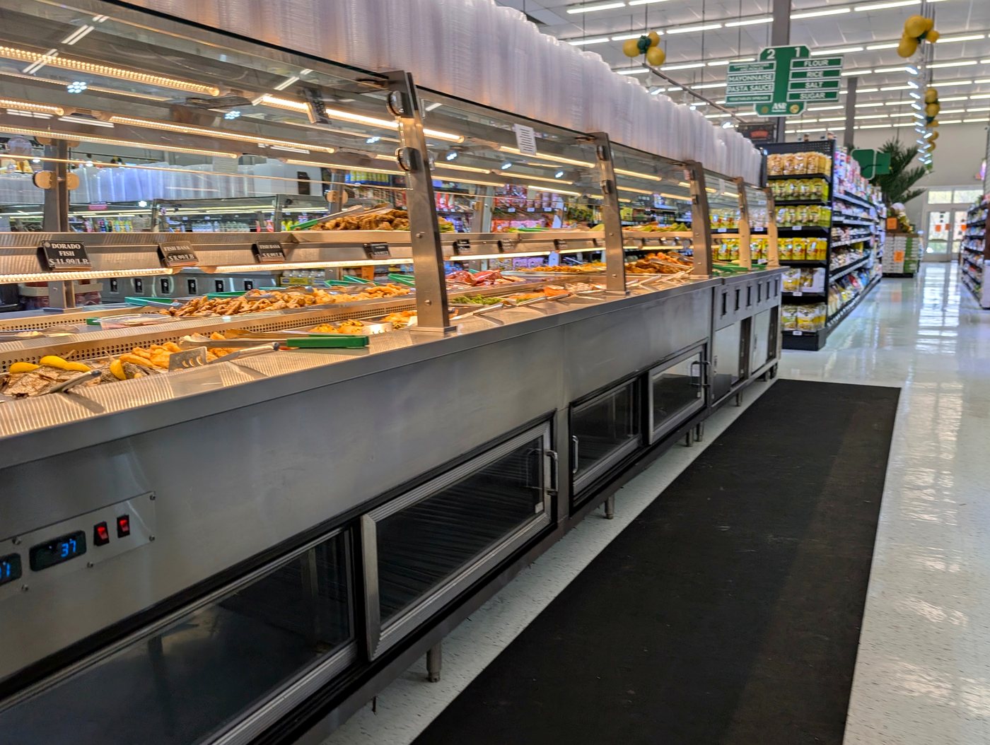 Long glass hot-food display case of prepared trays at ASR Food Market.